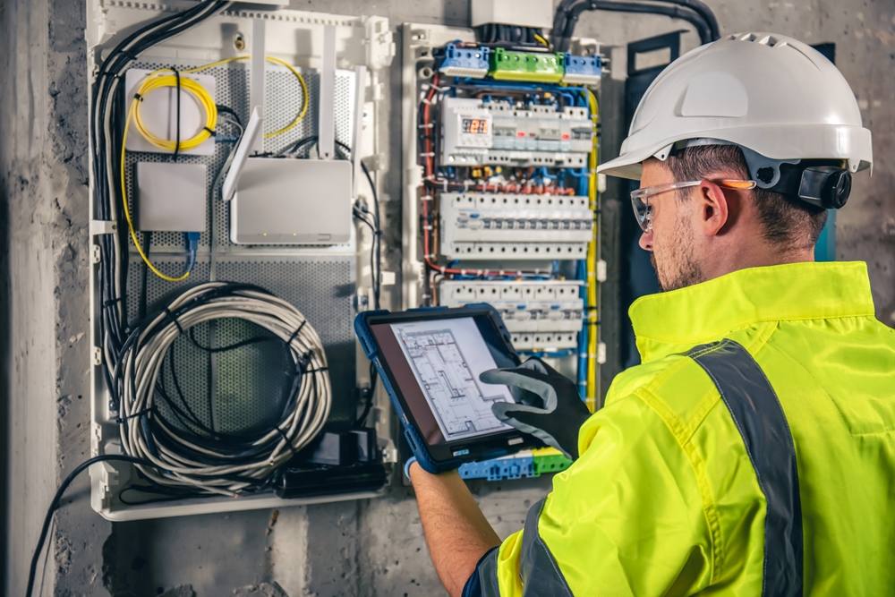 Commercial electrician checking a distribution board with a tablet