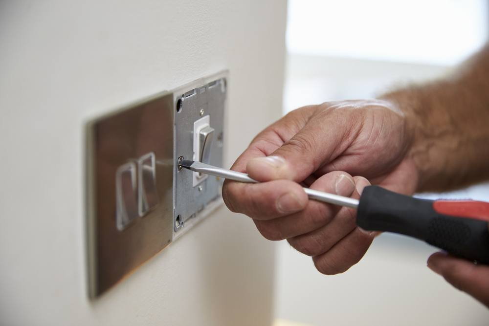 Electrician fitting a light switch in a home
